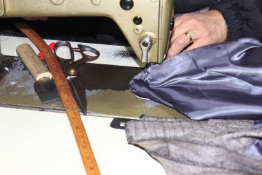 Kumaş makas ve cetvelle dikiş makinesi kullanan eller