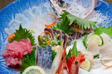 Mavi tabakta servis edilen çeşitli taze sashimi.