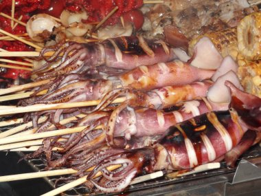 Piyasadaki şişler üzerinde ızgara mürekkep balıklarının yakın çekim görüntüsü