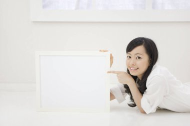 Beyaz gecelikli Japon kadın mesajın için boş beyaz pano tutuyor.