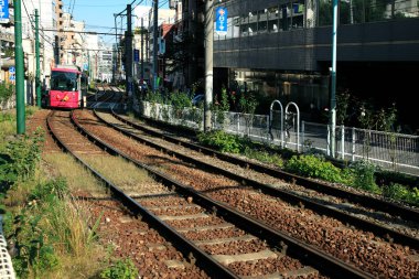 Somut sütunlar rayları destekliyor, hareketli şehir içindeki demiryolu koridorunu görsel olarak tanımlıyor.