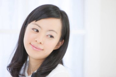 Zarif Japon kadın zarif bir şekilde minimalist beyaz bir odada poz veriyor..