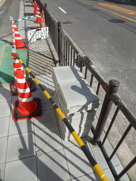 Trafik konilerinin yanındaki metal çitlerin yanına beton bloklar yığılmış.