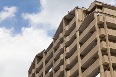 Balkonları, pencereleri ve mavi gökyüzü olan bina.