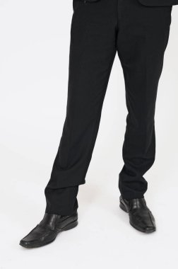 Beyaz arka planda duran siyah takım elbiseli iş adamının bacakları