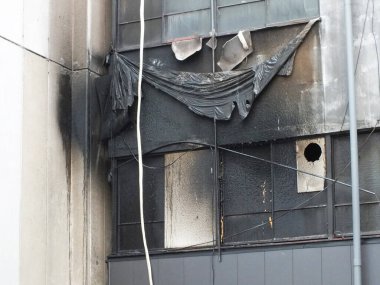 Yanmış binanın dış tarafı geniş çaplı yangın hasarı ve kararmış duvarlar gösteriyor.