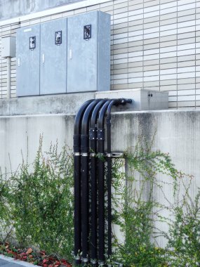 Dışarıdaki beton duvar boyunca uzanan elektrik boruları.