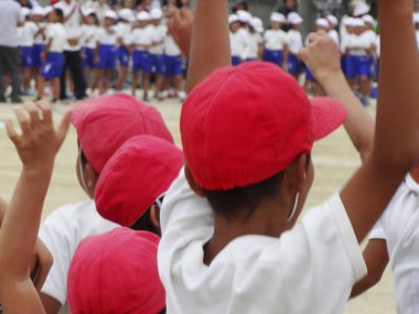 Kırmızı şapkalı çocuklar dışarıda el kaldırıyor.
