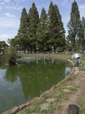 Şehir parkında şemsiyenin altında dinlenen balıkçı