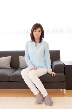 Güzel Asyalı kadın evdeki kanepede dinleniyor.