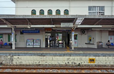 Yükseltilmiş demiryolu kolonları, yoğun Japon şehir manzarası boyunca ritmik bir şekilde yürüyor.