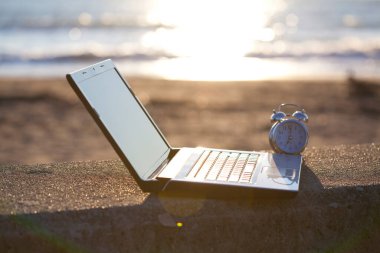 Günbatımında kumsalda alarmlı bilgisayar.    