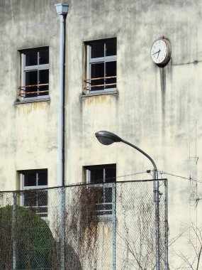 Pencereleri ve yuvarlak saati olan eski gri bina