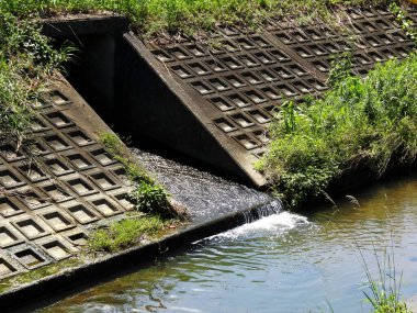 Beton drenaj kanalı durgun nehre yağmur suyu boşaltıyor