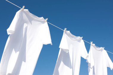 Temiz beyaz elbiseler mavi gökyüzüne karşı kuruyor.