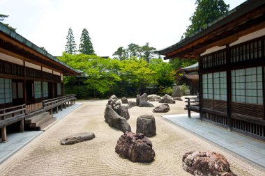 Güneşli bir günde taş düzenlemeleri ve geleneksel mimari ile huzurlu Japon bahçesi