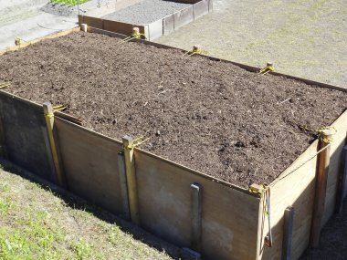 Dışarıdaki toprakla dolu büyük ahşap gübre kutusu.