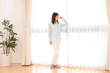 Dairede duran Asyalı kadın pencereye bakıyor.