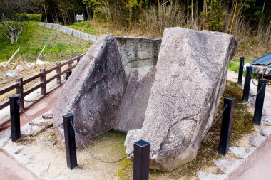 Tahta çitlerin yanında duran büyük antik taş yapı.