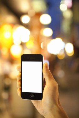 Kentsel arka planda boş ekranlı akıllı telefonu tutan kişinin kırpılmış görüntüsü