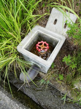 Su vanası çimen ve beton yapıyla çevrili.