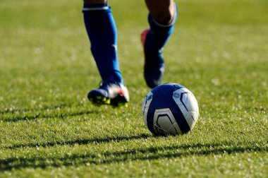 Spor giyim sektöründe futbol oyuncusunun bacakları çimlerin üzerinde top oynuyor.                 