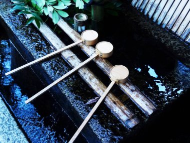 Dışarıdaki bambu su çeşmesinde dinlenen üç tahta kepçe.