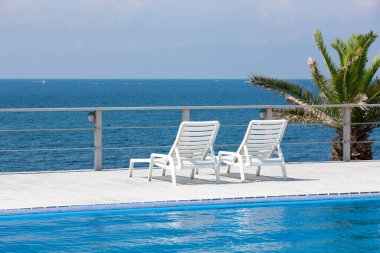 Güneş yatakları ve mavi deniz manzaralı boş yüzme havuzu alanı 