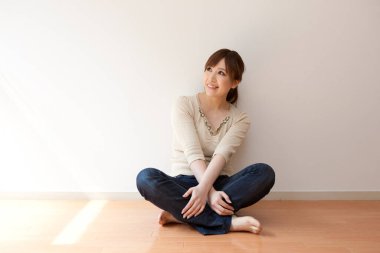 Japon kadın boş odada yerde oturuyor.