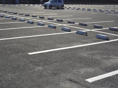 Boş otopark, park halindeki araçlar ve gün ortası güneş ışığı altında iyi tanımlanmış alanlar.