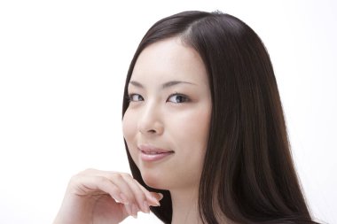 Güzel, genç Asyalı bir kadın beyaz arka planda yalnız gülümsüyor. 