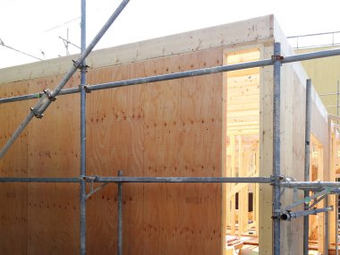 Modüler ahşap duvarların ve yeni bir bina inşaatı için metal iskelelerin yakın çekimi..
