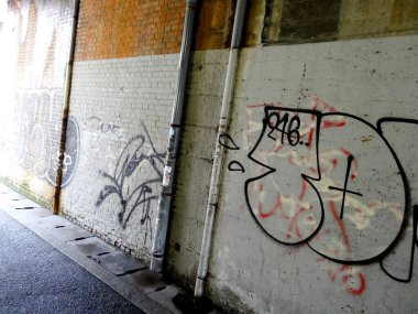 Renkli grafiti ve açıkta duran borulardan oluşan şehir tüneli duvarı.