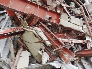 Bükülmüş metal kirişler kırık beton döküntülerinin arasına dolanmış.