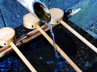 Bambudan akan temiz su ahşap kepçelere akıyor.