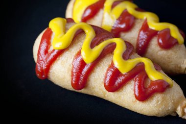 Sosisli ve ketçaplı sosisli sandviçleri yakın.