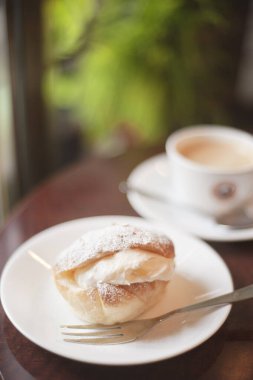 Bir fincan kahve ve ahşap masada taze çörekle nefis bir kahvaltı.