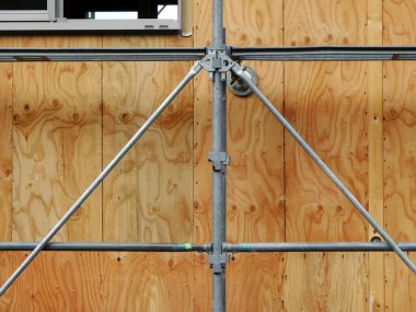 İnşaat alanındaki metal iskeleler ve ahşap duvarlar.