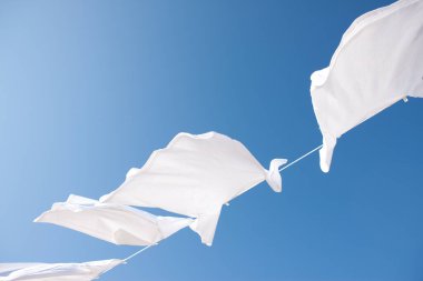 Temiz beyaz elbiseler mavi gökyüzüne karşı kuruyor.