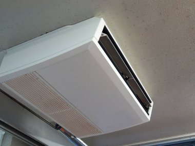 Pencerenin üzerinde asılı beyaz tavan klima ünitesi