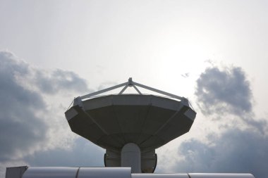 Bulutlu, parlak gökyüzüne bakan büyük uydu anteni