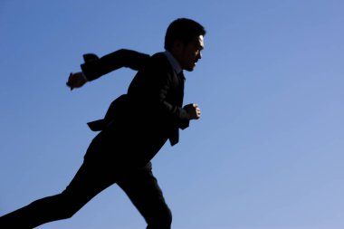 Genç iş adamı mavi gökyüzü arka planında çalışıyor