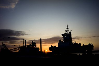 Renkli günbatımı gökyüzüne karşı vinç ve gemi siluetleri