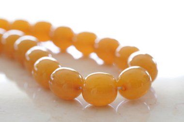 Parlak turuncu boncuklar zarif bir kolye düzeni oluşturuyor.