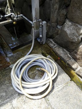 Bahçe hortumu dışarıda taş duvarın yanında dinleniyor.