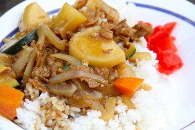 Lezzetli kızartılmış sebze ve et tabakta canlı süslerle pilav üzerine servis edilir.