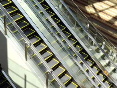 Modern binanın içindeki boş yürüyen merdivenlere güneş ışığı vuruyor.