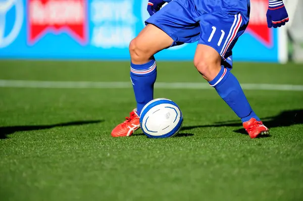 草の上のボールで遊ぶスポーツウェアのサッカー選手の足 — ストック写真