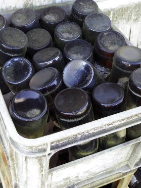 Dışarıdaki plastik sandıkta boş cam şişeler yığılıyor.