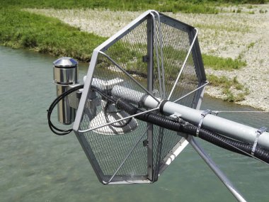 Akan su yüzeyinin üzerine uzanan metalik nehir izleme aygıtı